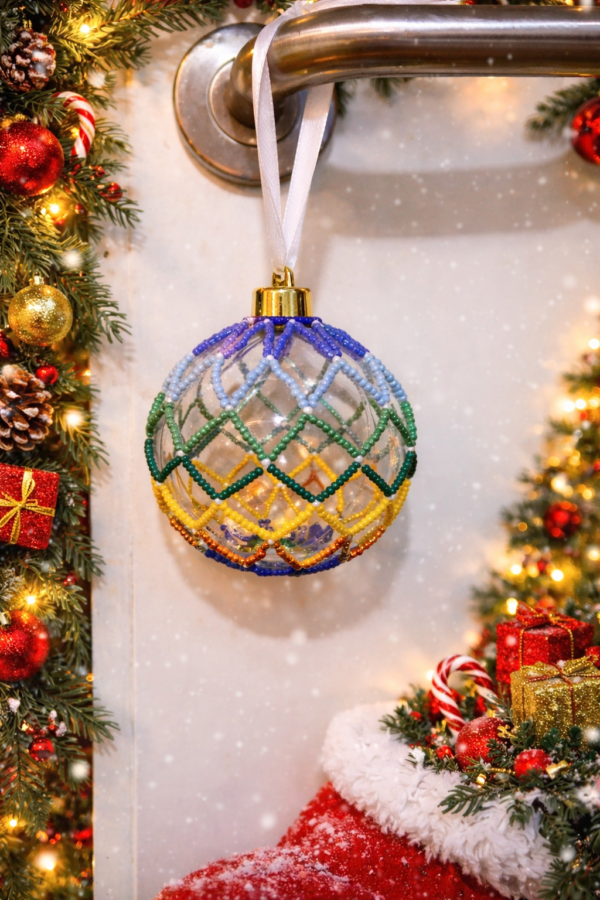 Handmade multicolour beaded Christmas bauble with chevron pattern on a clear plastic ornament hanging from a door handle