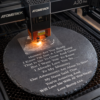Atomstack A20 Pro laser engraver engraving a personalised baby scan ultrasound image onto a round slate plaque.