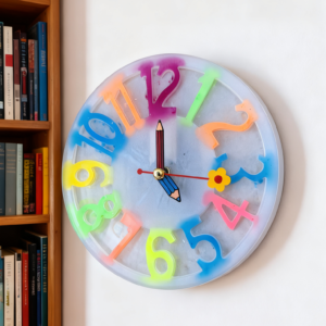 Colourful handmade children's wall clock featuring bright rainbow numbers and pencil-shaped clock hands. Perfect for helping children learn to tell the time while adding fun colour to a bedroom, nursery, playroom, or classroom.