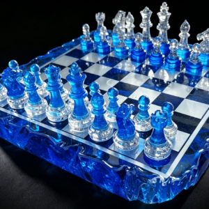 Handmade-Blue-Resin-Chess-Set-with-Geode-Edge-Board Handcrafted resin chess set featuring translucent blue and clear abstract pieces on a glossy board with a raw, geode-style crystal edge, lit against a black background.