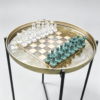 Round resin chess table with fern inlay, gold rim, clear and teal chess pieces, and black folding metal legs